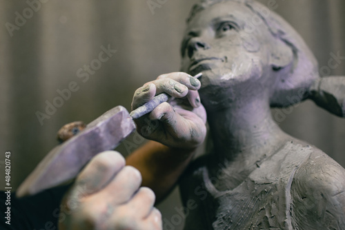 Man sculptor creates sculpt bust human woman sculpture with hammer. Statue craft creation workshop.