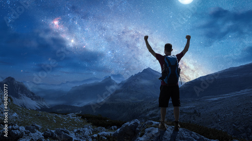Hiker in the mountains under a starry night sky