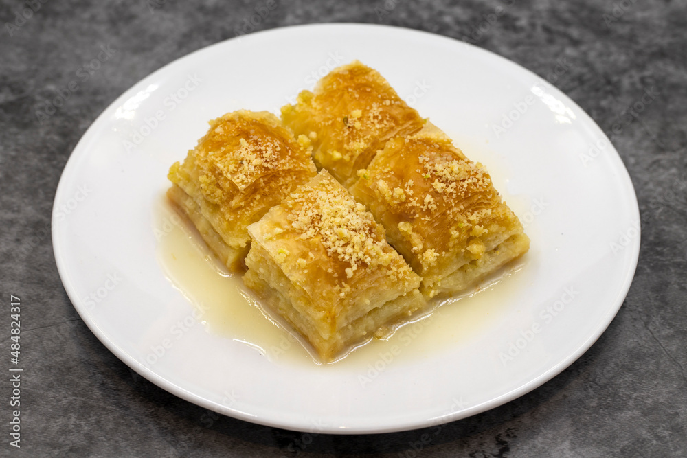 Baklava with milk (sutlu nuriye). Baklava with hazelnut and milk on a dark background. Baklava with milk (sutlu nuriye). Baklava with hazelnut and milk on a dark background.