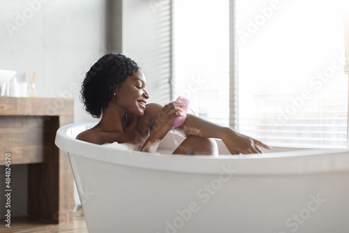 Relaxed african american young woman taking bath, side view