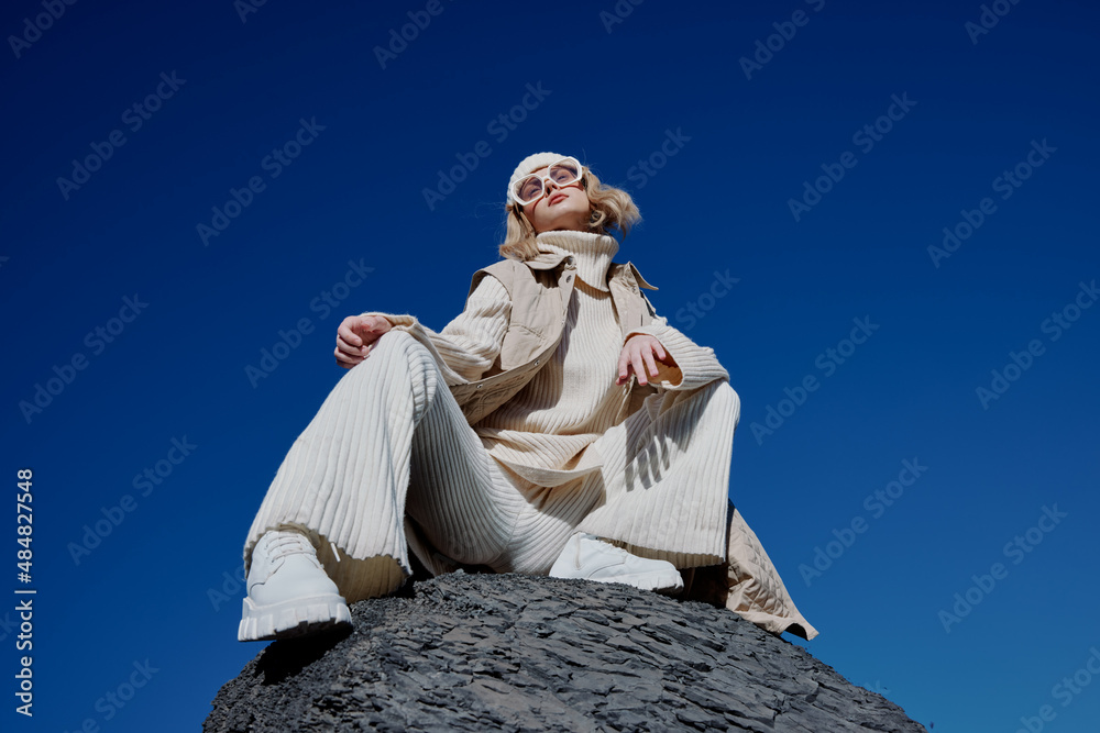 Fototapeta premium young woman sitting on a stone nature blue sky in a hat lifestyle