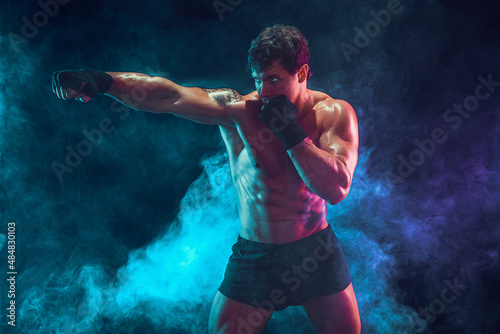 Half length of athlete boxer who training and practicing jab on smoke background. Sport concept