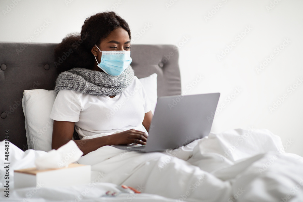Sick african american woman in face mask surfing on Internet Sick african american woman in face mask surfing on Internet