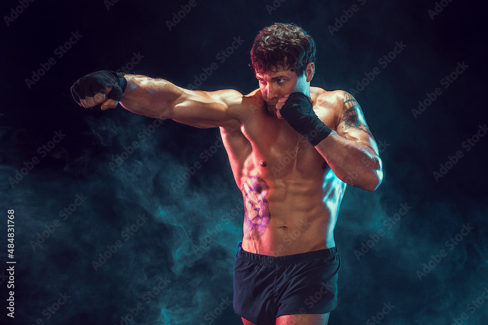 Half length of muscular boxer who training and practicing jab on smoke background. Sport concept