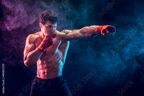 Portrait of aggressive boxer who training and practicing jab on smoke background. Sport concept