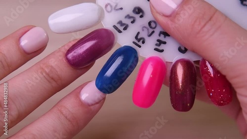 woman chooses the color of gel nail polish for manicure