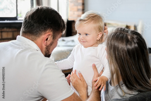 Young parents sit on the couch and hug the baby. High quality photo