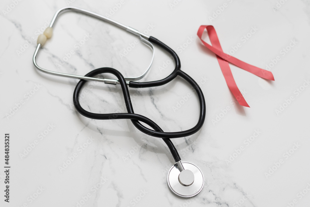 red ribbon with a cancer day phonendoscope. women's and men's health red ribbon with a cancer day phonendoscope. women's and men's health