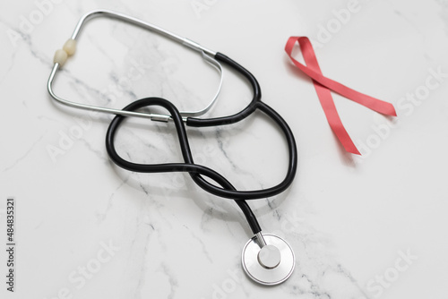 red ribbon with a cancer day phonendoscope. women's and men's health