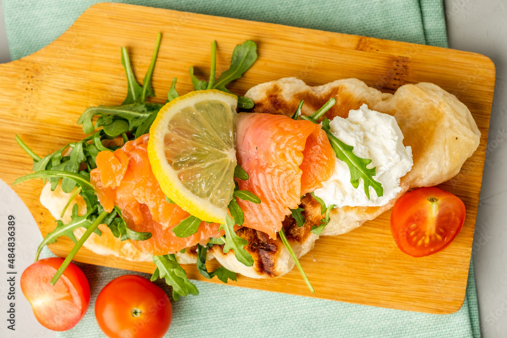 Sandwich with salted salmon and curd cheese, arugula. croffle with salmon top view.