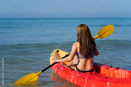 woman in swimsuit paddling a kayak boat in sea