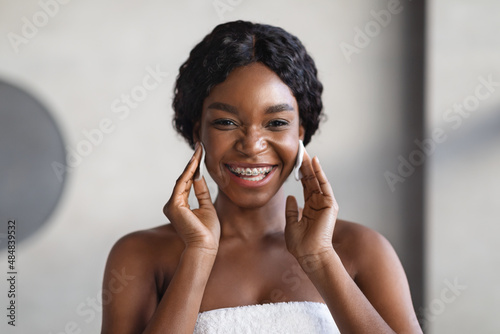 Attractive young black woman using cotton pads