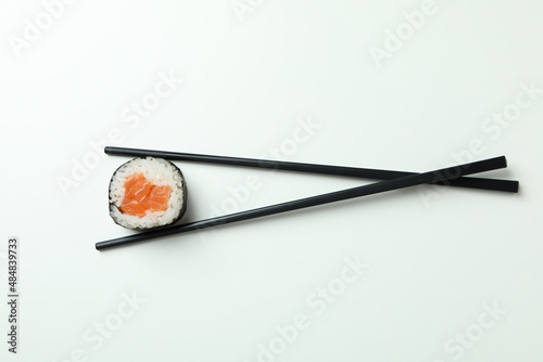 Chopsticks with maki on white background, top view
