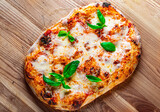 flatbread Pizza with Mozzarella cheese, Tomatoes, pepper, Spices and Fresh Basil. Italian pizza. Pizza Margherita or Margarita on wooden background