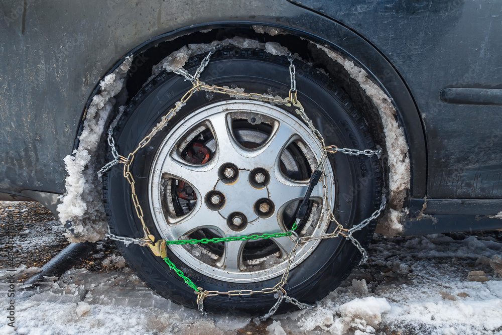 Snow chains on a car wheel. The fenders of the car are by the