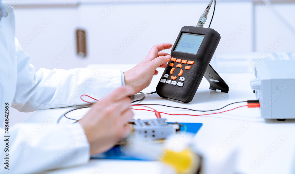 woman electronics laboratory measures multimeter circuit board parameters