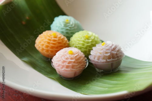 Thai dessert flower shape stuff with crushed soybean and taro on wood table with banana leaf and white dish. (Thai name is Khanom Chor Phaka Krong) photo