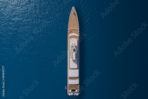 Big yacht for millionaires in the sea drone view. Big white super ship in the ocean aerial view.  Luxurious white mega yacht on blue water in the reflection of the sun top view. © Berg