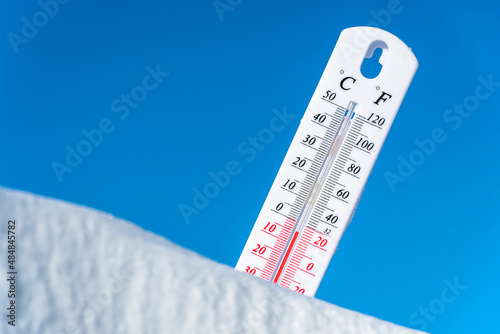 Thermometer in the snow. Climate, weather, forecast. Temperatures outside. Thermometer in the snow shows temperatures below zero. Low temperatures in degrees Celsius and fahrenheit in snowy weather