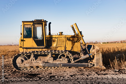 Powerful heavy crawler bulldozer works at a construction site in the evening against the background of the sunset sky. Construction equipment for earthworks.