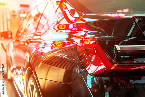 Fragment with a stop light of a modern expensive car in the light of colored lamps and reflections.