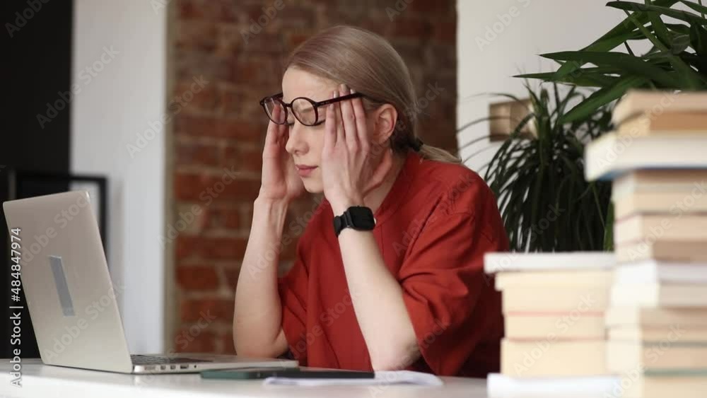 Tired woman working on her laptop in home office Tired woman working on her laptop in home office