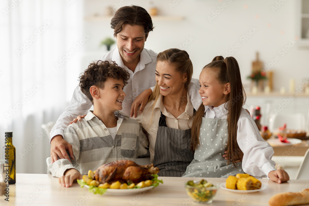 Loving parents and children posing together in kitchen, cooking tasty meal for family Christmas celebration at home Loving parents and children posing together in kitchen, cooking tasty meal for family Christmas celebration at home