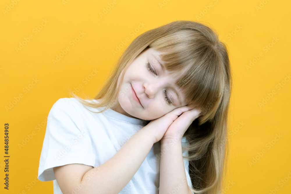 cute smiling sleepy calm girl with closed eyes folded her palms under her head. dreaming on yellow background close up cute smiling sleepy calm girl with closed eyes folded her palms under her head. dreaming on yellow background close up