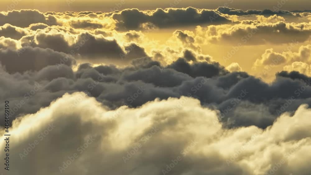 Flying above the clouds. Aerial tele shot dense veil of clouds illuminated by the setting sun. Epic flight in the sky with clouds, sunset in the sky