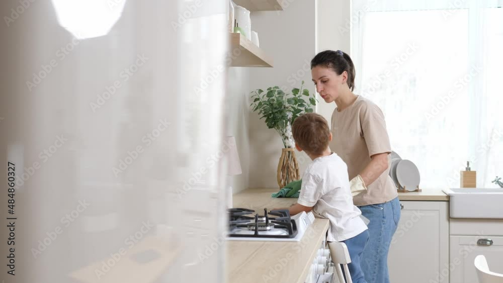 Close-up of a happy woman and her little son dusting with a rag on a dirty dusty shelf. Child helps mom with cleaning. House cleaning Close-up of a happy woman and her little son dusting with a rag on a dirty dusty shelf. Child helps mom with cleaning. House cleaning