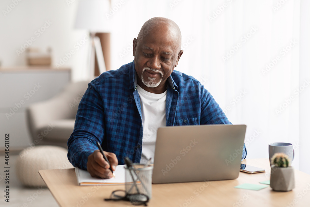 Senior Black Man At Laptop Taking Notes Indoors Senior Black Man At Laptop Taking Notes Indoors