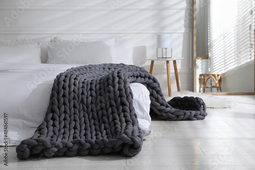 Soft chunky knit blanket on bed in stylish room interior photo