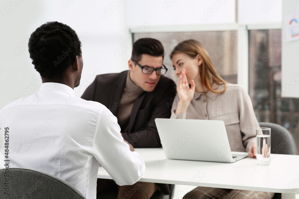 Coworkers conducting job interview with African American man in office. Racism concept Coworkers conducting job interview with African American man in office. Racism concept