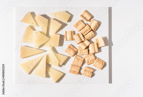Trozos de queso manchego de oveja curado con tostadas de pan crujiente sobre una mesa blanca. Tapas españolas. Vista superior photo