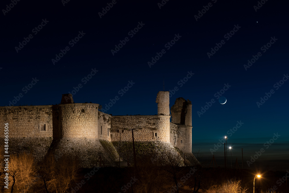 Fototapeta premium night falls over the castle of chinchón, the moon and neptune guard it. medieval castle with the moon at its side