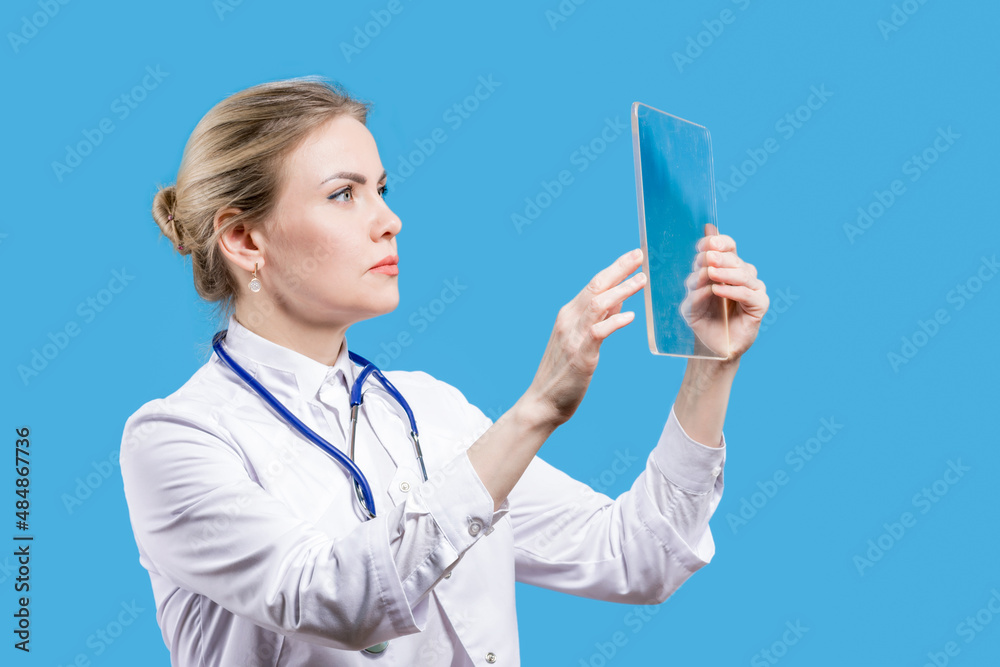 Hospital. Analyzes from the laboratory. Therapist. Chief Physician. A female doctor looks into a tablet on a blue background Hospital. Analyzes from the laboratory. Therapist. Chief Physician. A female doctor looks into a tablet on a blue background