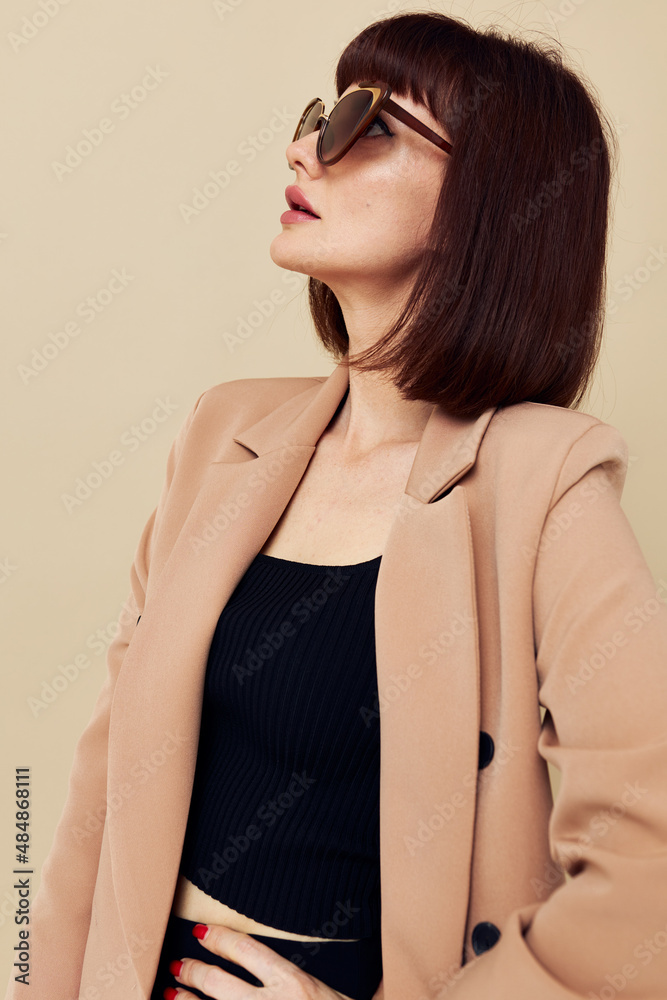 Obraz premium portrait of a woman in a beige jacket elegant style sunglasses light background