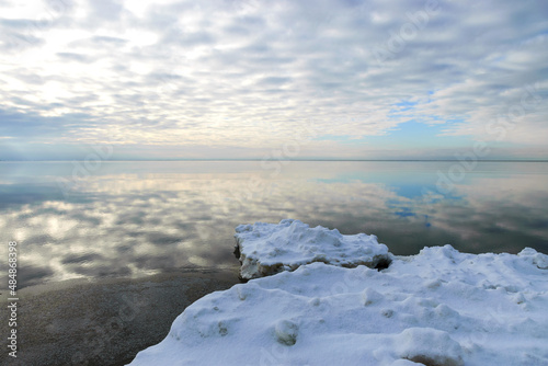 Winter seascape, slow freezing sea, glorious skies, white pieces of ice by the sea