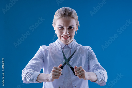 A female doctor holds scissors in her hands on a blue background. Circumcision. Veterinarian Hospital. Castration. Treatment photo