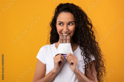 Funny Latin Lady Holding And Biting Chocolate At Studio