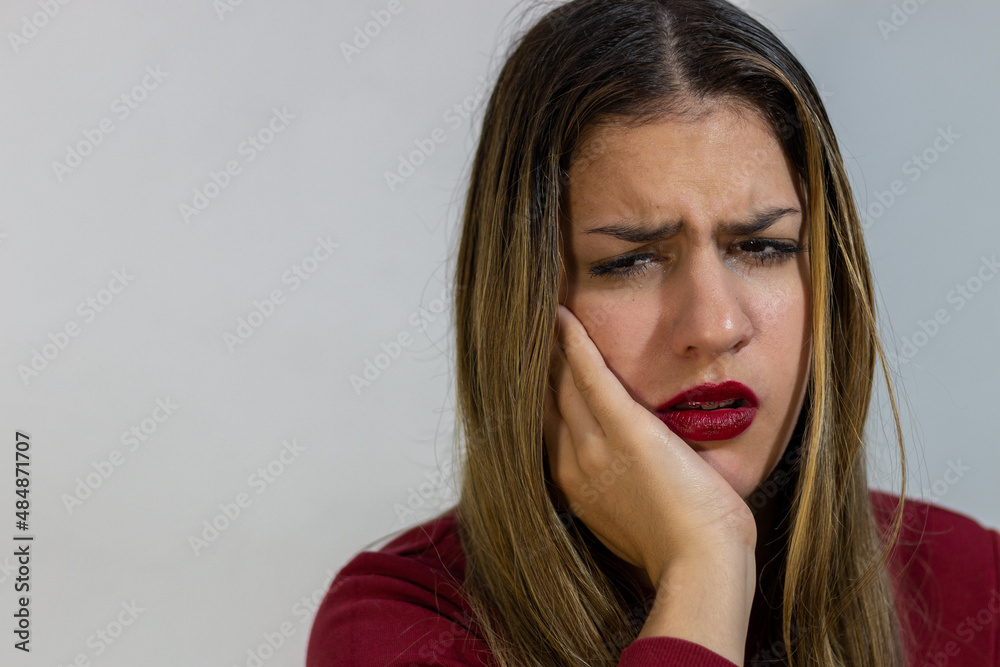 A young worried girl having strong toothache and touching her cheek A young worried girl having strong toothache and touching her cheek