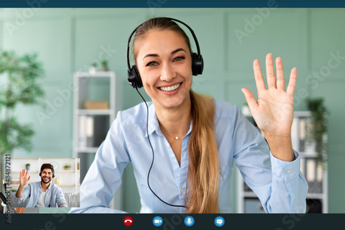 Fotografía Happy female teacher wearing headphones while having video conference, waving an