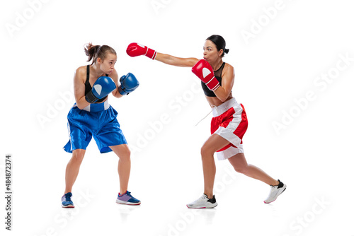 Dynamic portrait of two female professional boxers boxing isolated on white studio background. Couple of fit muscular caucasian athletes fighting. Sport, competition photo