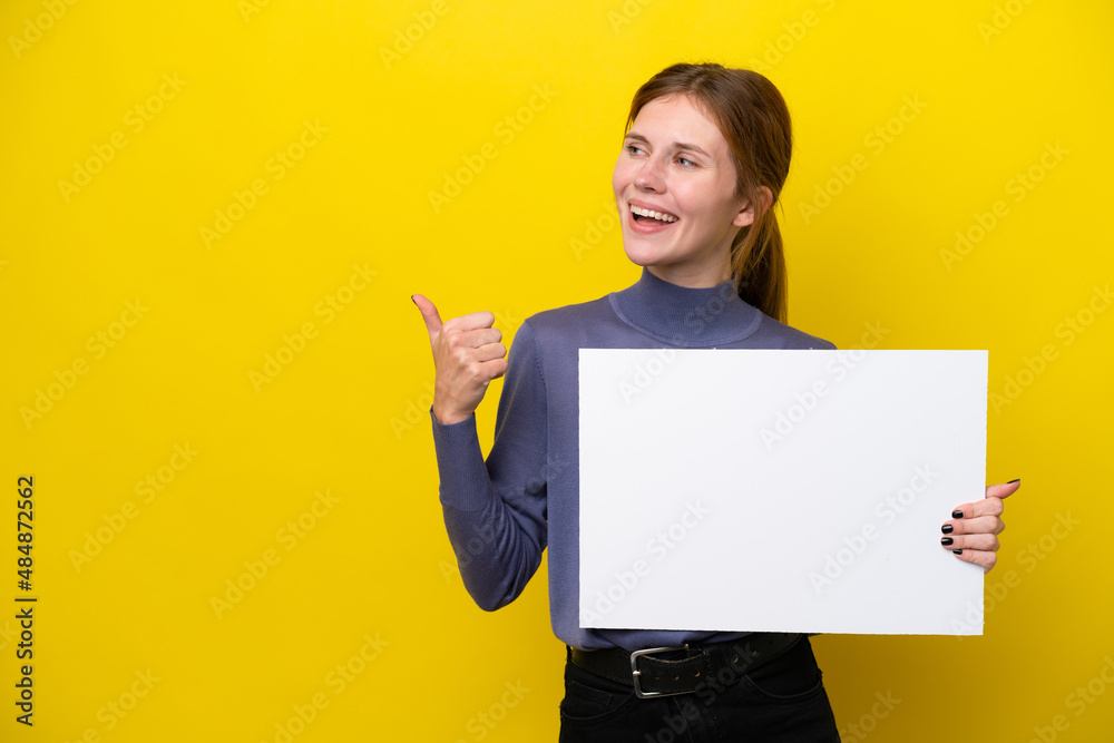 Young English woman isolated on yellow background holding an empty placard and pointing side Young English woman isolated on yellow background holding an empty placard and pointing side