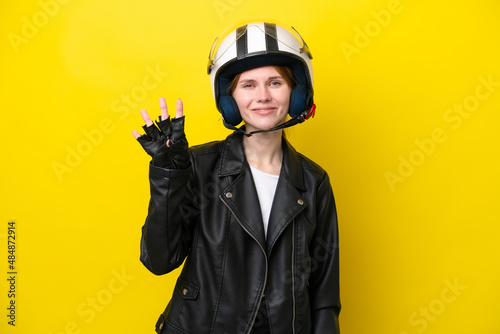 Young English woman with a motorcycle helmet isolated on yellow background happy and counting four with fingers