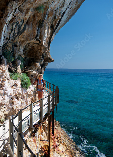 Blonde woman enjoying sunny day walking near the sea in Sardinia, summer holidays. Summer holidays concept. Active vacation