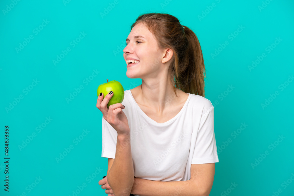 Young English woman isolated on blue background with an apple and happy Young English woman isolated on blue background with an apple and happy