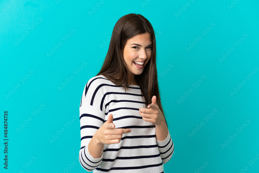 Teenager Brazilian girl over isolated blue background pointing to the front and smiling Teenager Brazilian girl over isolated blue background pointing to the front and smiling