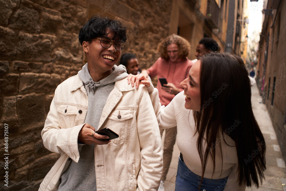 Fototapeta premium Group of happy friends using phone outdoors while walking and laughing.