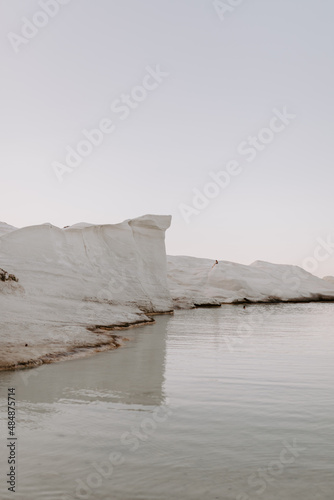 The sandstone white rocks cliffs moonscape of Sarakiniki volcanic beach in Milos Island Greece surrounded by turquoise blue waves and sea at sunset